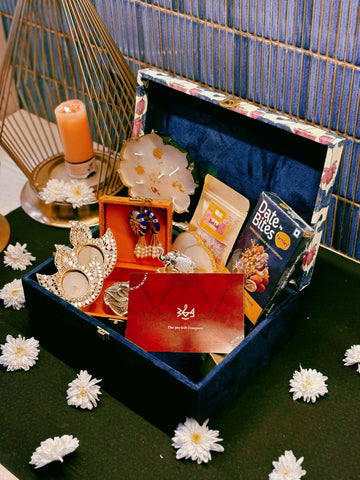 Luxury handcrafted wedding gift hamper by The 369 Gift Company, featuring an Urli Oudh candle, tealight holders, resin coasters, bath salts, chocolates, and decor accents in a lotus trunk box — perfect for weddings, events, and festive gifting.