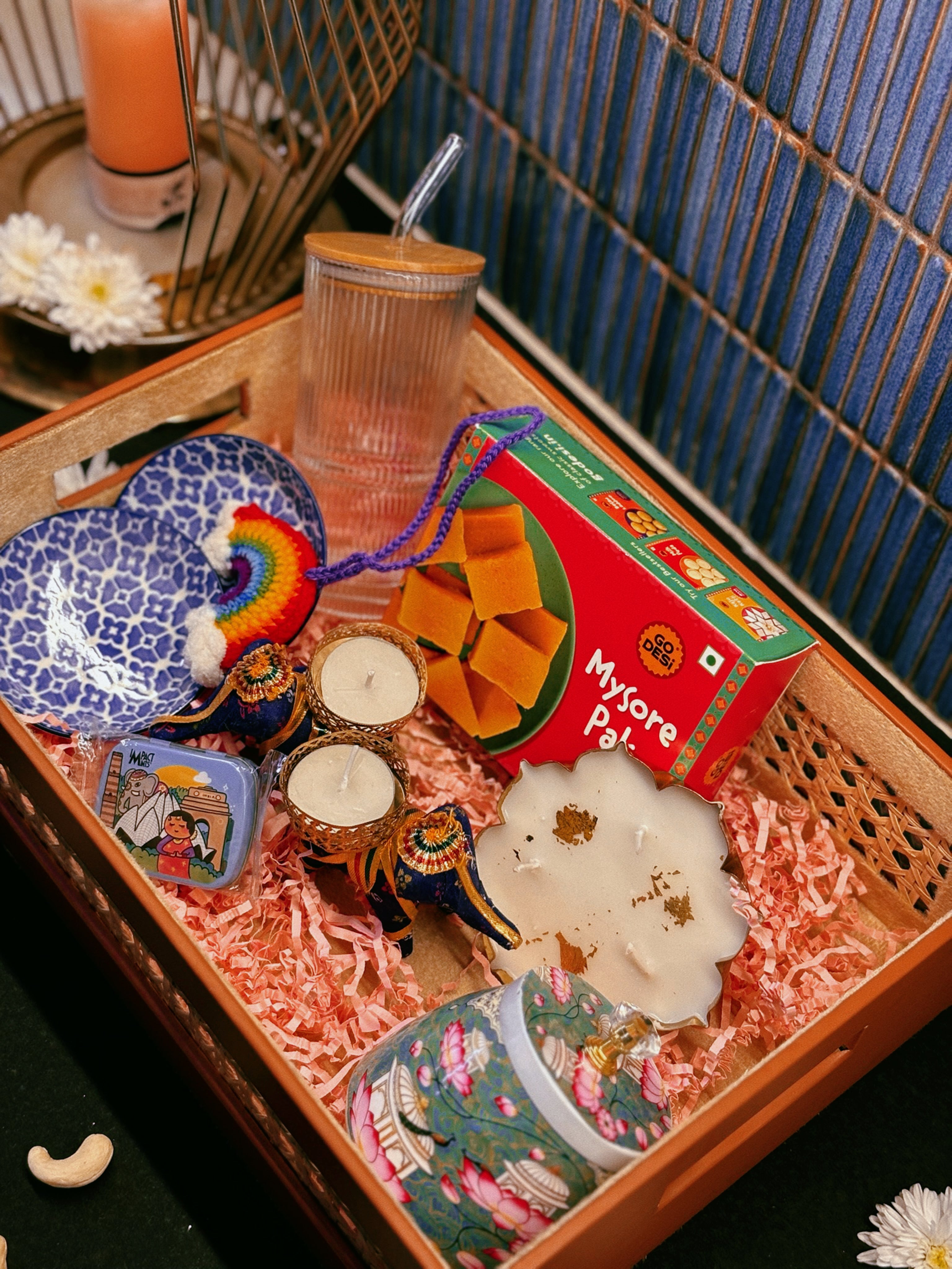 Luxury handcrafted wedding and event hamper by The 369 Gift Company — featuring a rattan tray with mocha leather detailing, Mysore pak, Urli Oudh candle, elephant tealight holders, nuts and seed-filled Pichwai metal jar, festive mints, rainbow crochet charm, starter bowls, and glass coffee tumbler — perfect for wedding favours, event gifting, and festive celebrations.