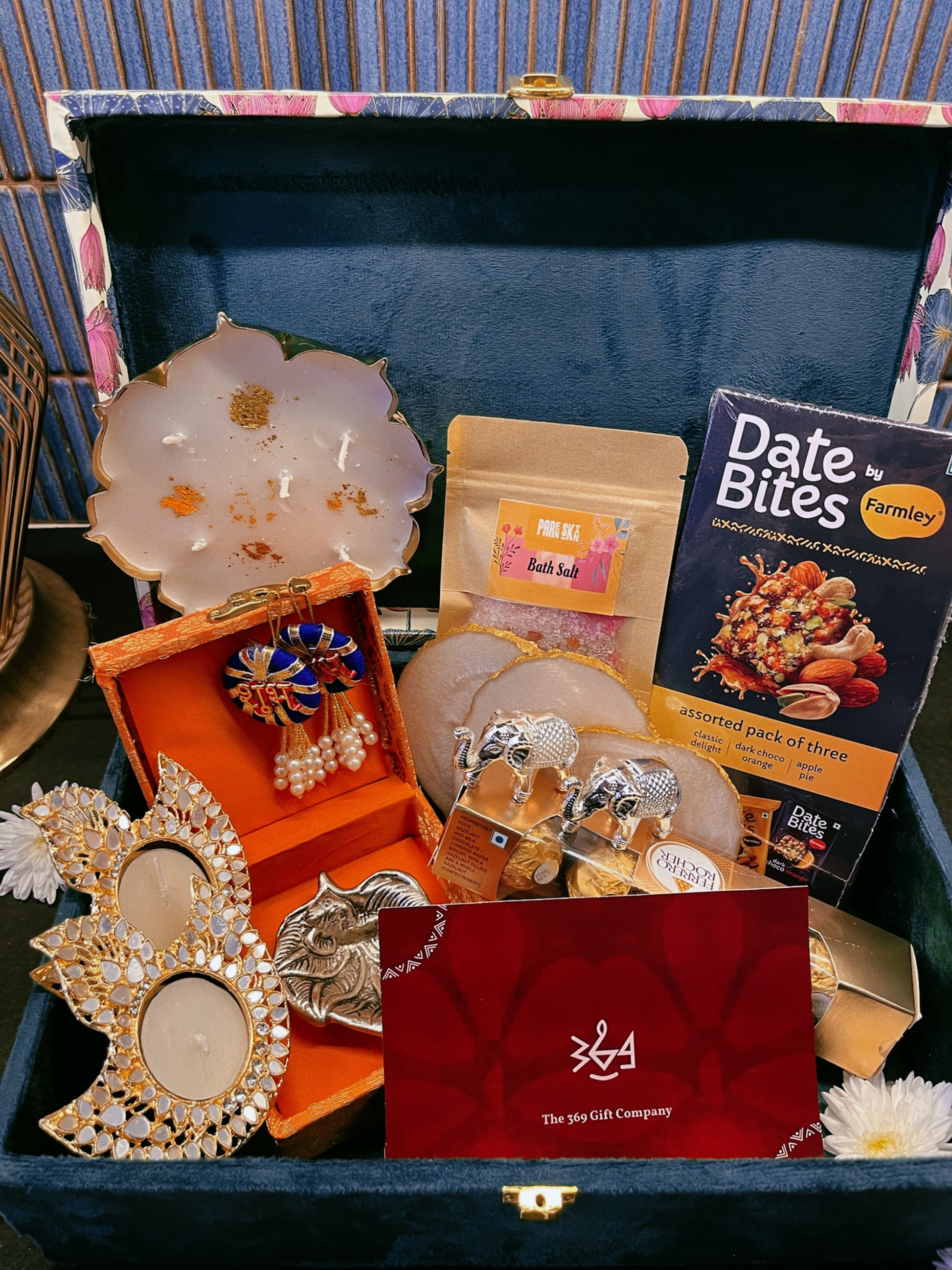Luxury handcrafted wedding gift hamper by The 369 Gift Company, featuring an Urli Oudh candle, tealight holders, resin coasters, bath salts, chocolates, and decor accents in a lotus trunk box — perfect for weddings, events, and festive gifting.